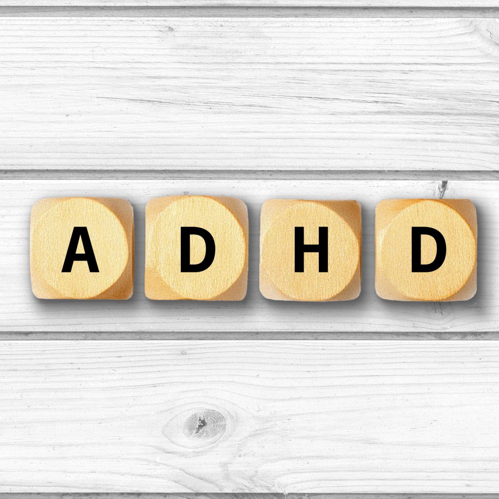 Dice blocks spelling out ADHD on a wood background